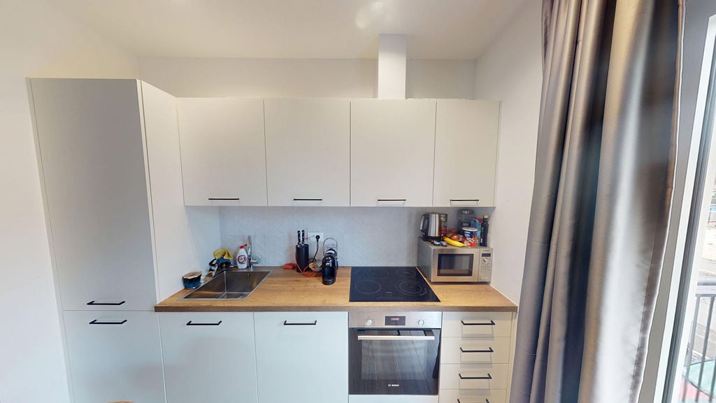 Modern white kitchen with a wooden countertop and built-in appliances in an apartment, Luštica, Montenegro.