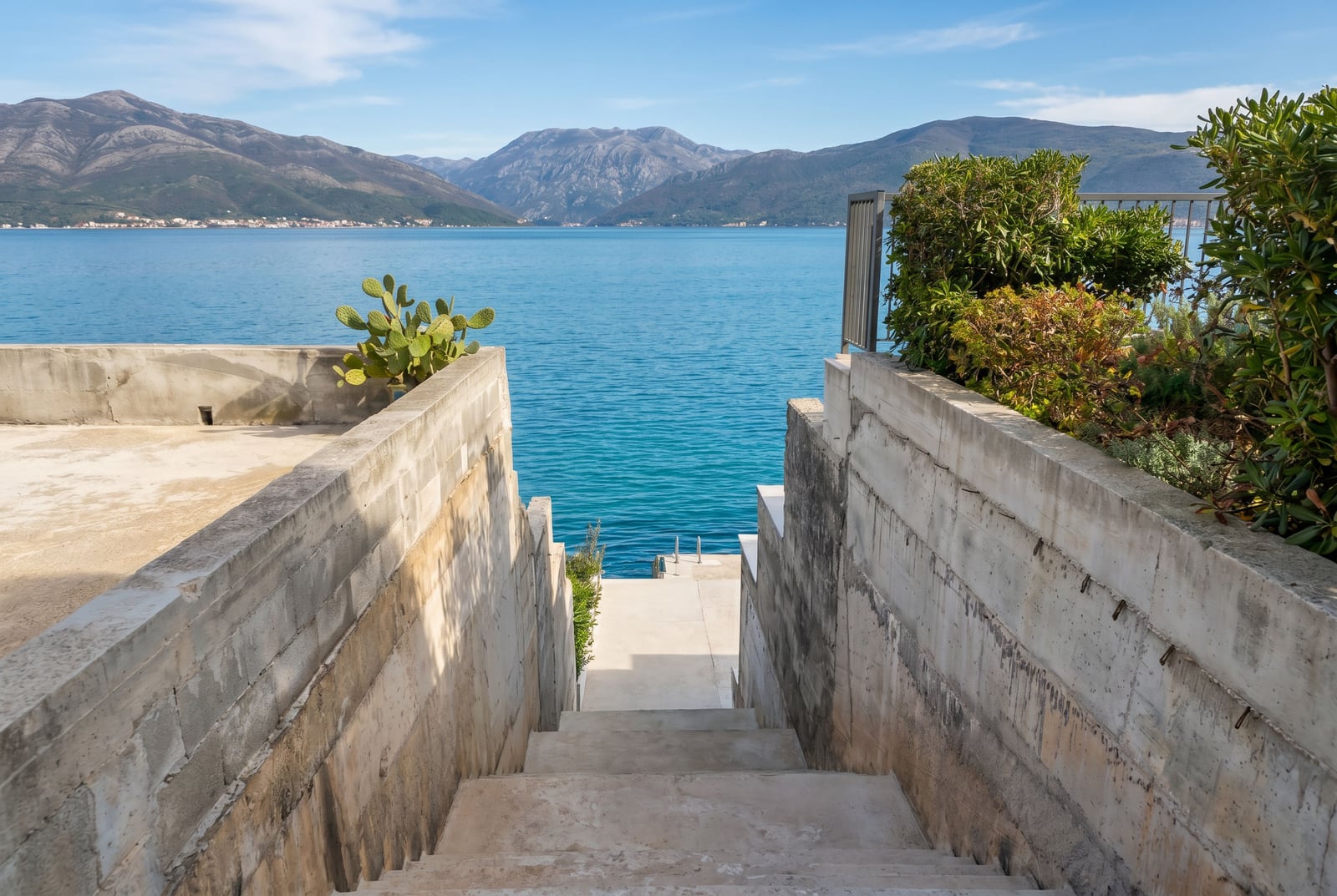 Concrete stairs leading to the sea and a private pier at a house in Krašići, Montenegro, with a panoramic view of the Bay of Kotor.