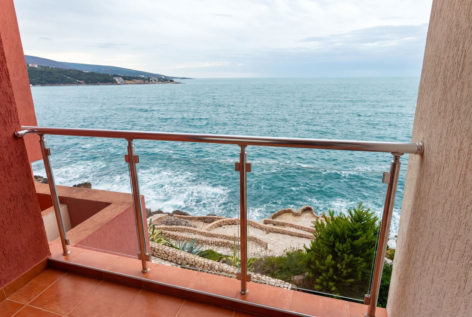View from the apartment balcony in Bar, Montenegro: panoramic sea view, rocky coastline, and modern glass railings.
