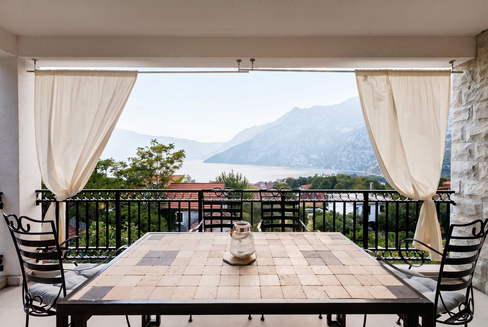 Terrace with a dining table and panoramic view of the Bay of Kotor and mountains in Risan, Montenegro.