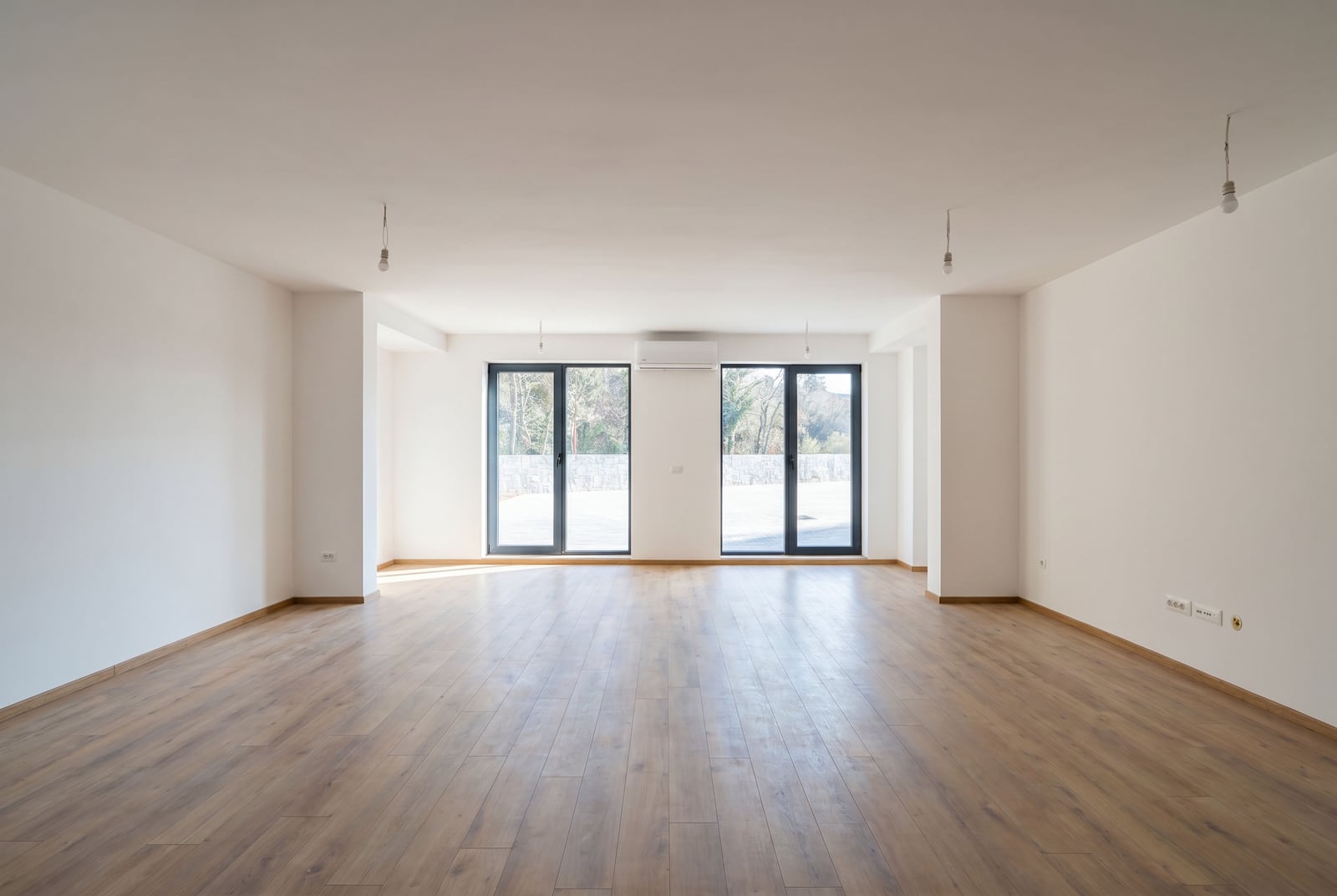 Bright living room with parquet flooring and panoramic windows in an apartment in Pržno, Montenegro. Modern unfurnished interior.
