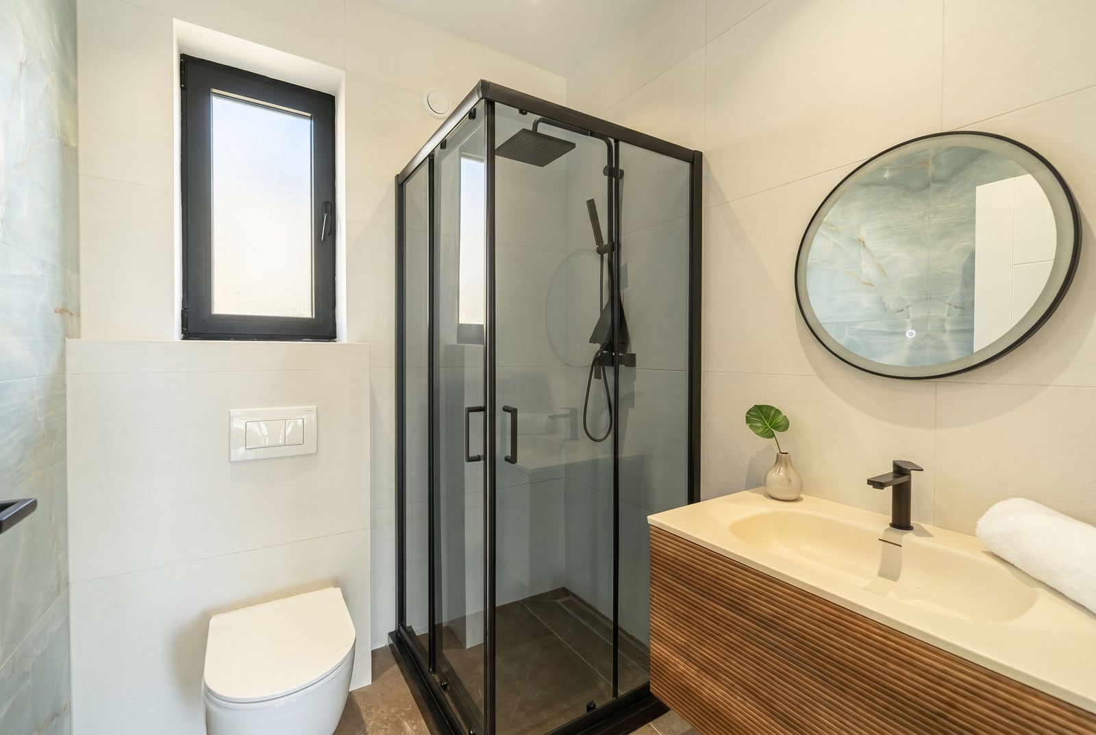 Modern bathroom in a townhouse, Kavač, Montenegro: walk-in shower, stylish vanity, and round mirror.