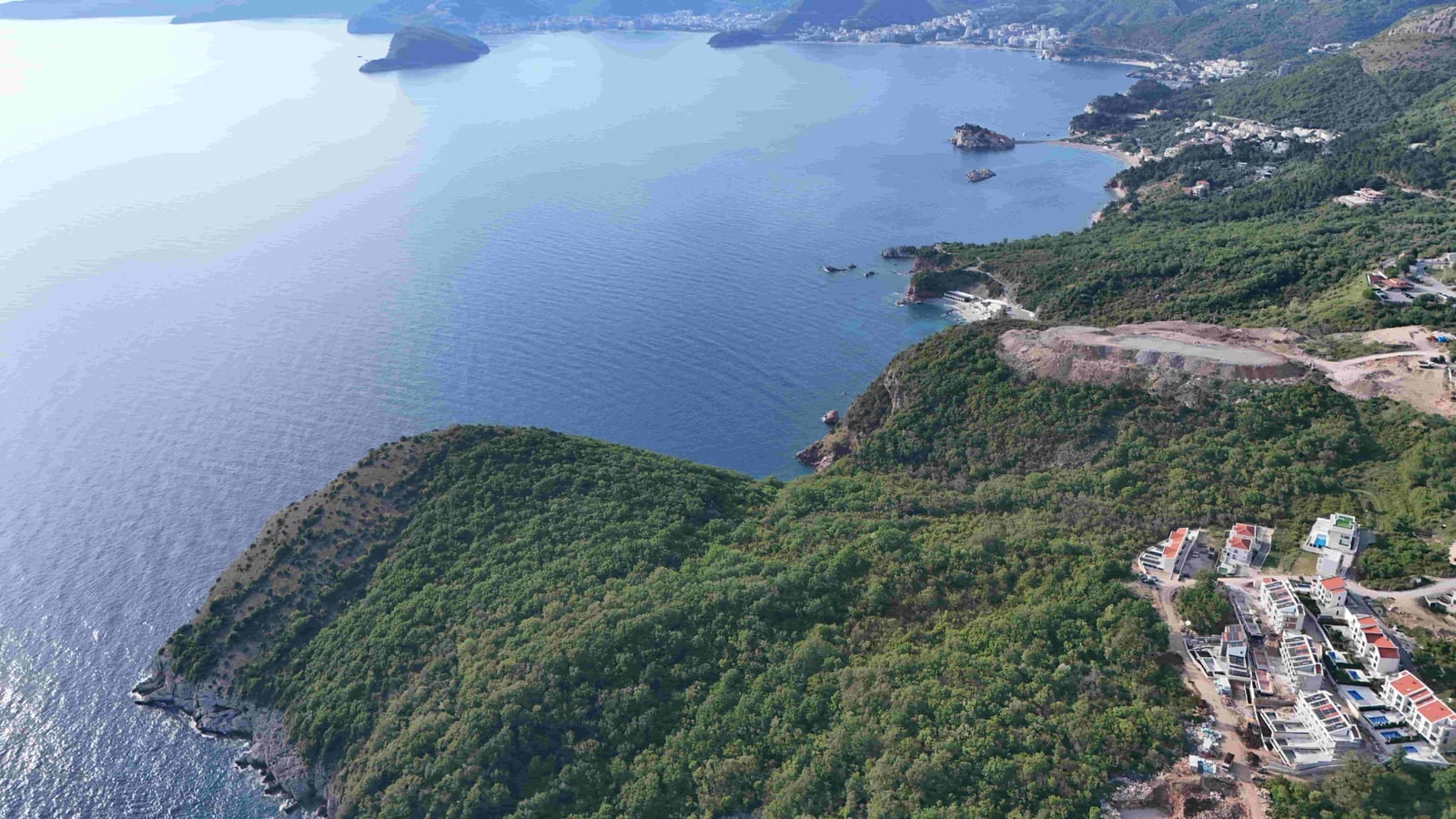 Aerial panoramic view of a land plot in Reževići, Montenegro, with a scenic view of the Adriatic Sea.