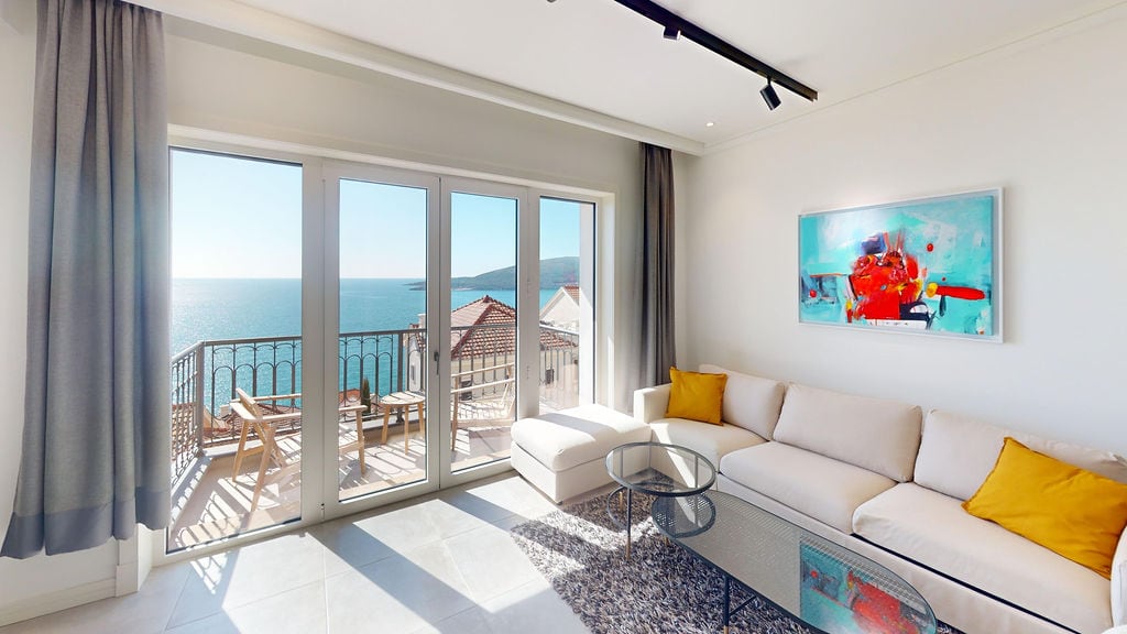 Living room with panoramic sea view in an apartment, Luštica, Montenegro: bright interior, terrace, and stylish furniture.