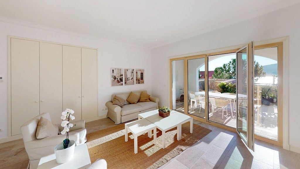 Bright living room in an apartment, Luštica, Montenegro: soft furniture, panoramic windows, and access to a terrace with a sea view.