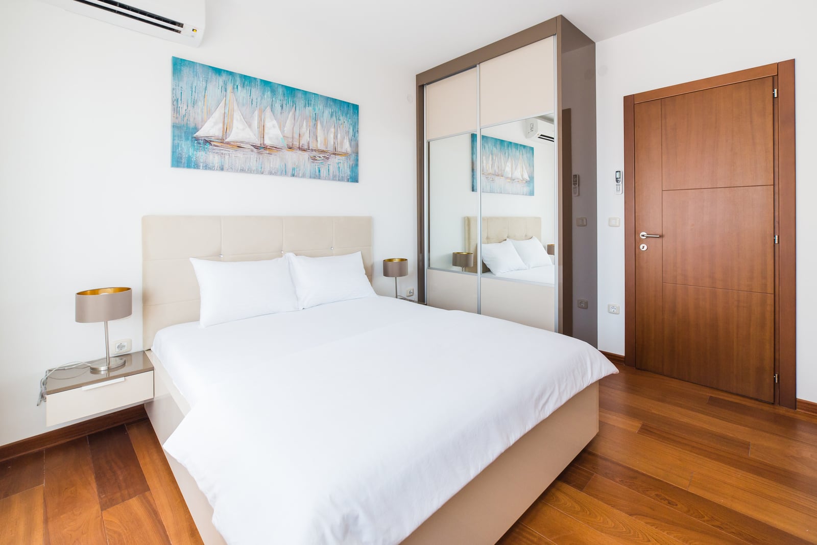 Modern bedroom with a double bed and a mirrored wardrobe in an apartment in Bečići, Montenegro.