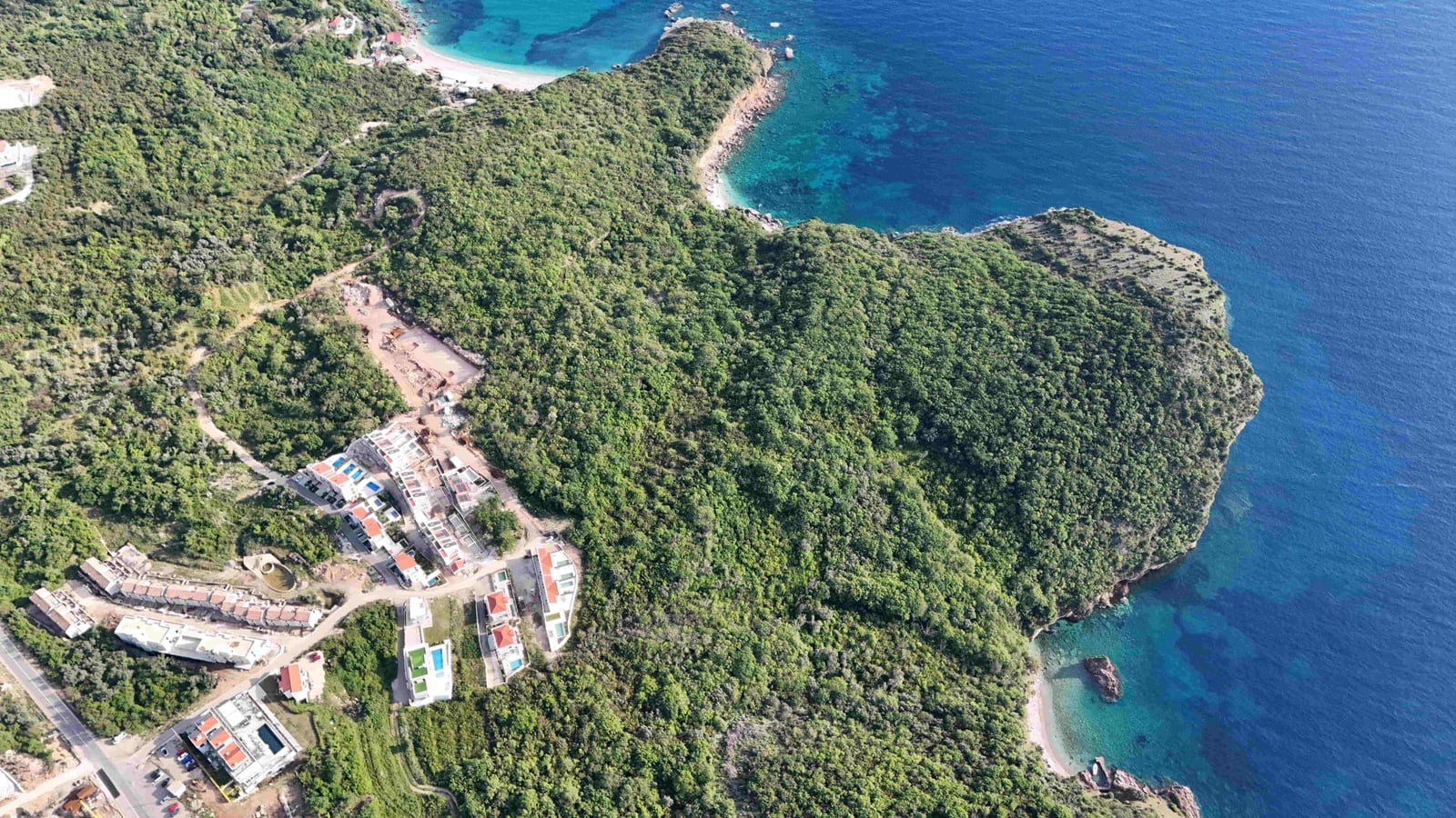 Aerial view of a land plot and villas in Reževići, Montenegro: the Adriatic Sea coast and dense forest.