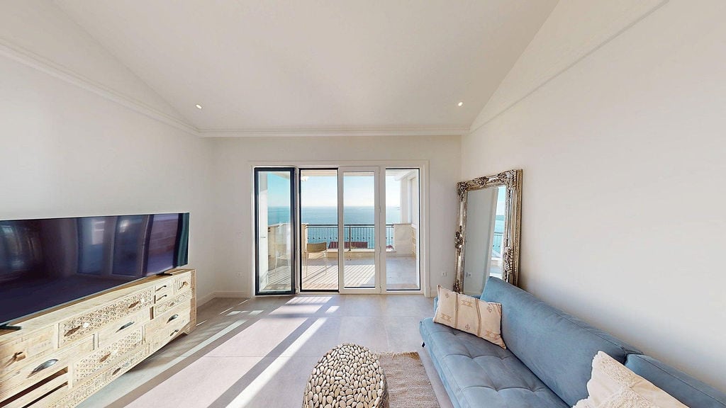 Bright living room in Luštica Bay apartments, Montenegro: blue sofa, carved cabinet, and panoramic sea view from the terrace.