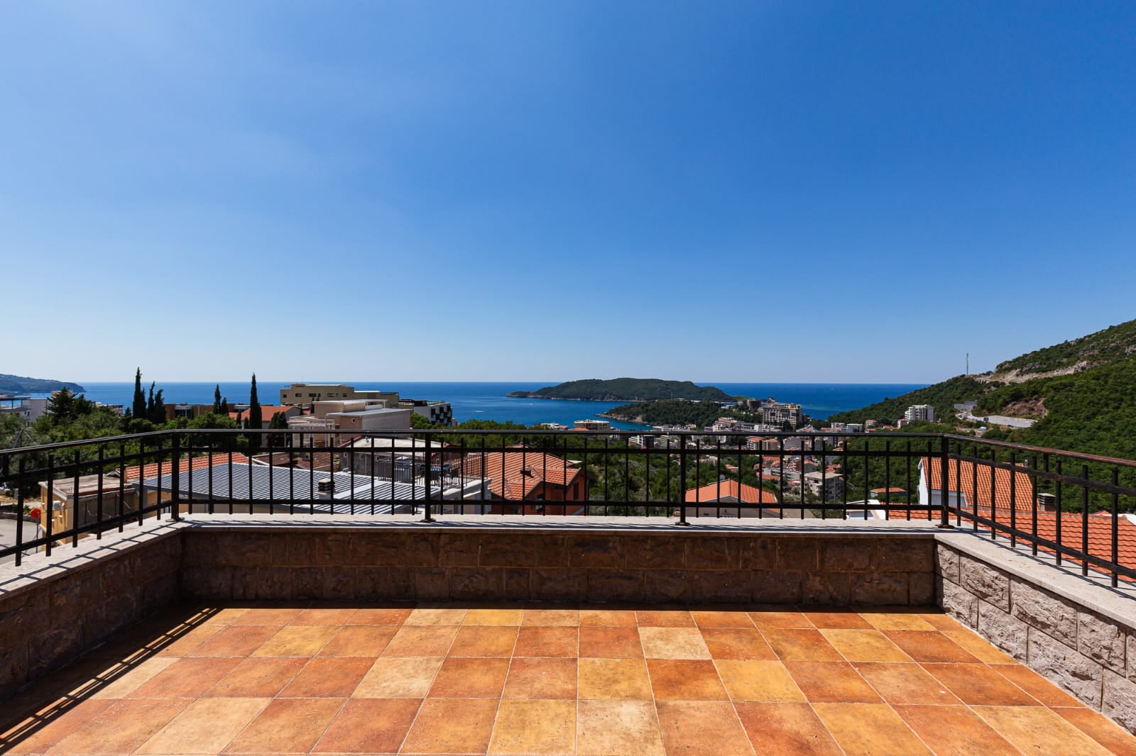 Spacious villa terrace in Bečići, Montenegro, with panoramic views of the sea, mountains, and the town's tiled roofs.