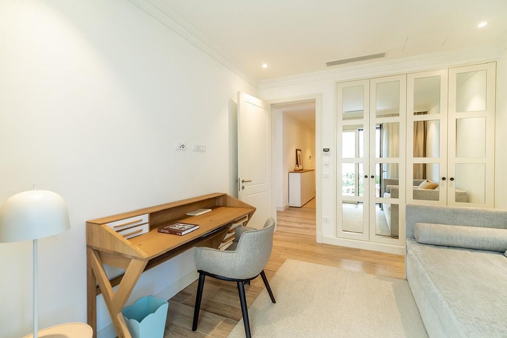 Bright bedroom with a desk and mirrored wardrobe in an apartment in Luštica, Montenegro. Modern interior.