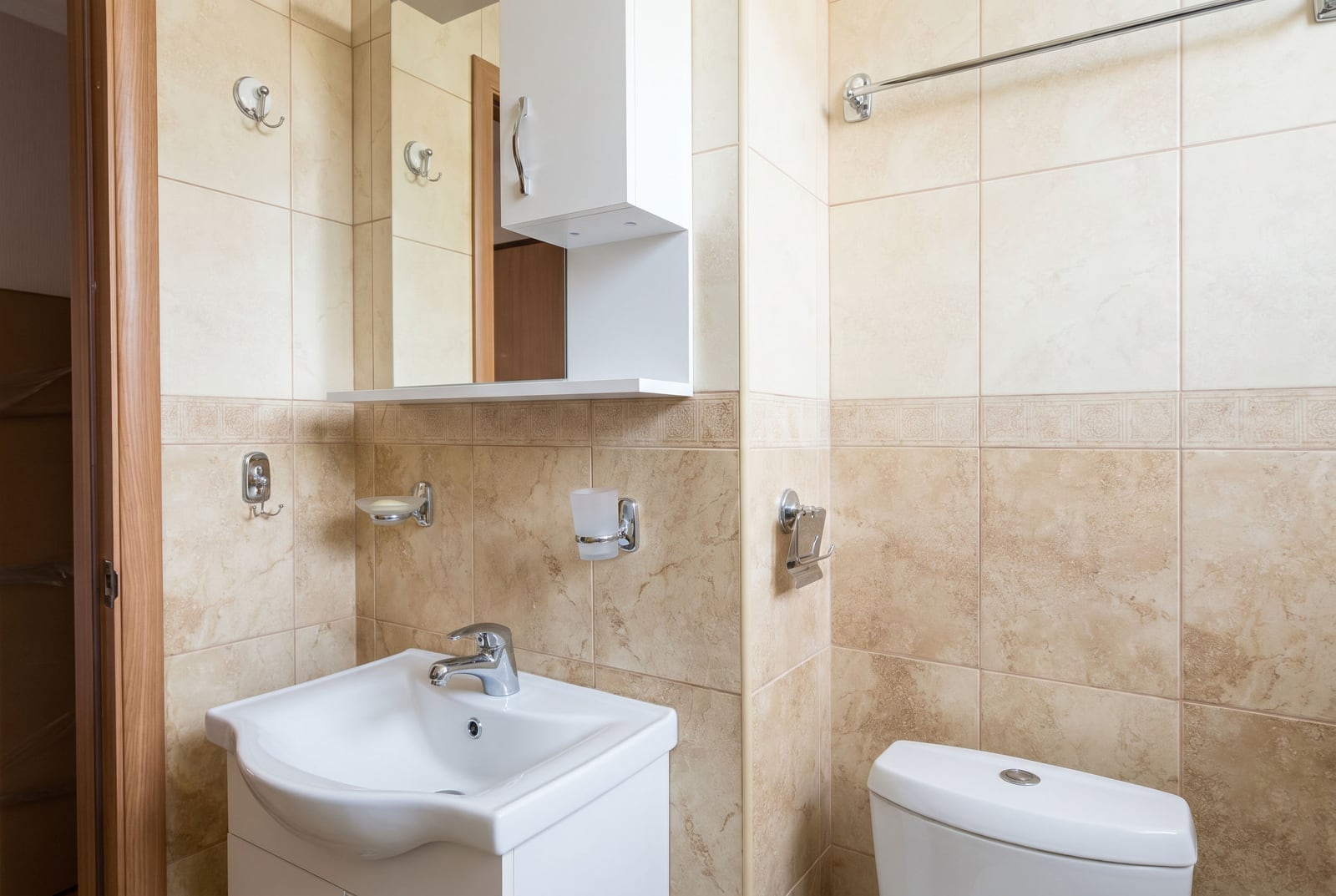 Bright bathroom with white sanitary ware and beige tiles in an apartment, Budva, Montenegro.