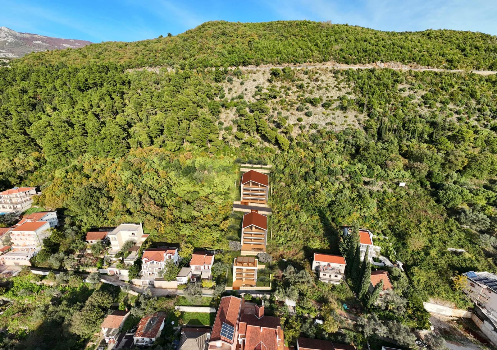 Aerial view of a building plot in Budva, Montenegro, surrounded by dense forest and private houses.