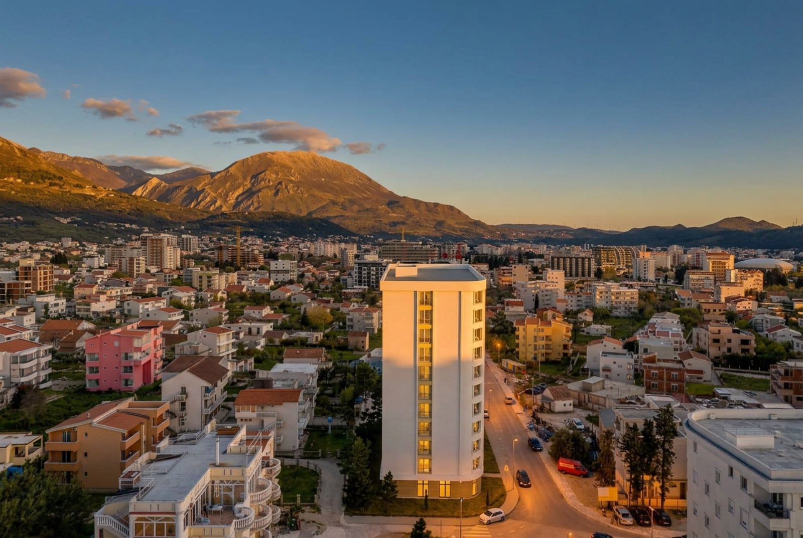 Modern residential complex in Bar, Montenegro, with panoramic views of the mountains and cityscape at sunset.