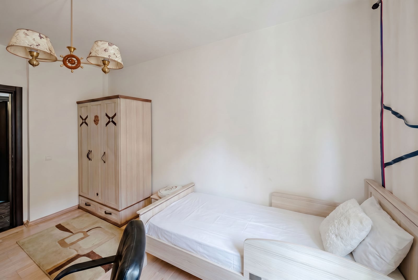 Bright bedroom with a single bed and wardrobe in an apartment, Kumbor, Montenegro. Cozy interior with a chandelier.