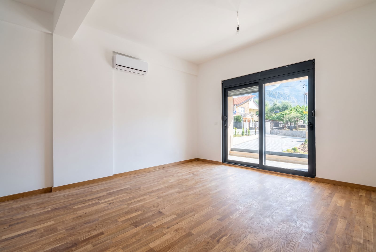 Bright empty living room with parquet flooring, air conditioning, and a panoramic window in Montenegro, city of Bar