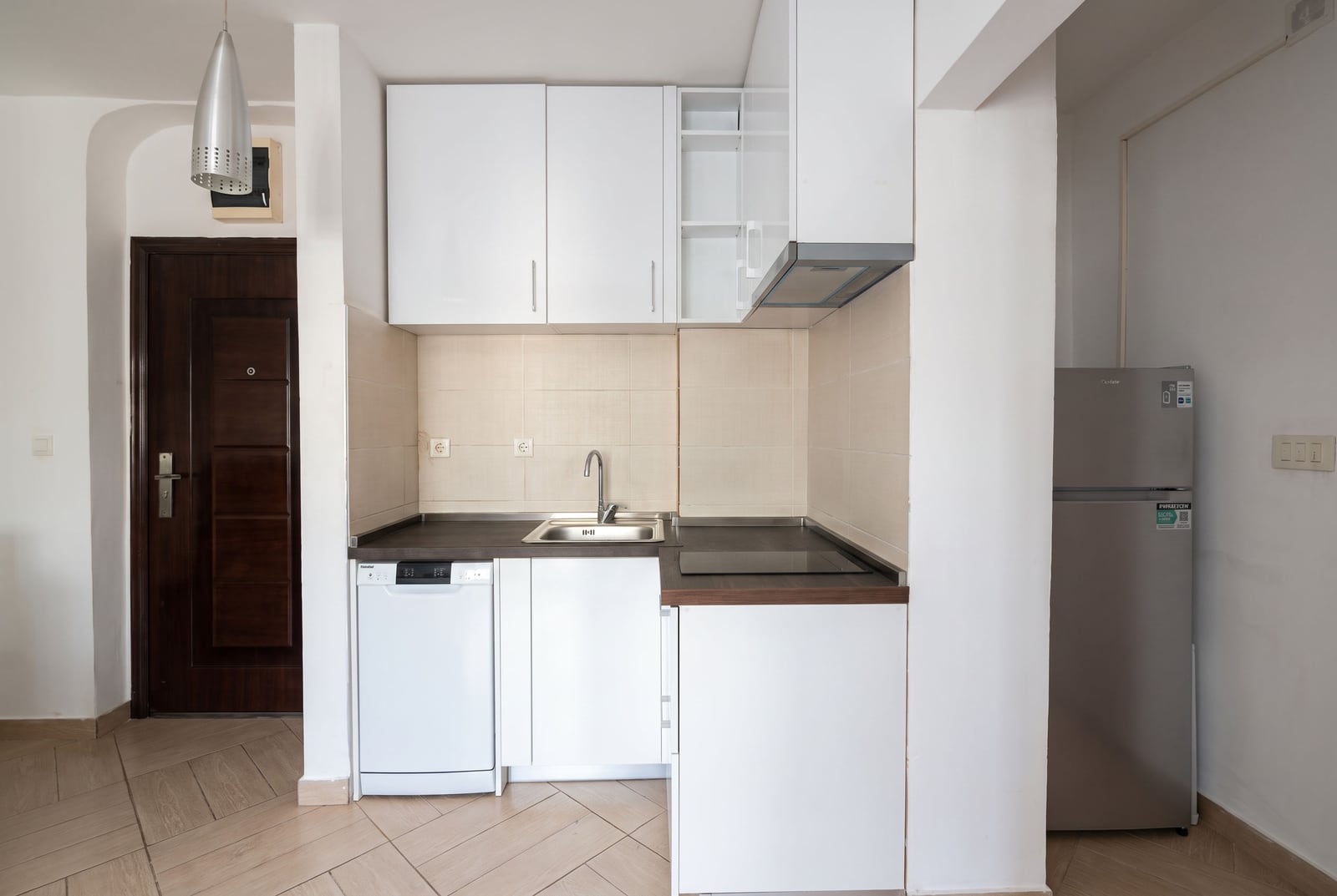 Compact white kitchen with furniture, sink, and appliances in an apartment in Budva, Montenegro