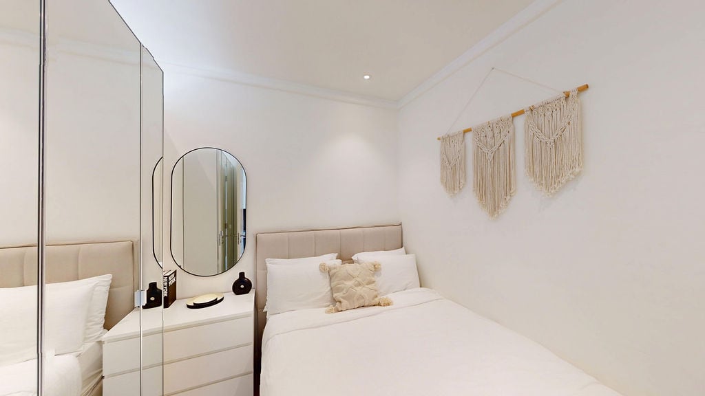 Bright bedroom in an apartment in Luštica, Montenegro: double bed, mirrored wardrobe, and boho-style decor.