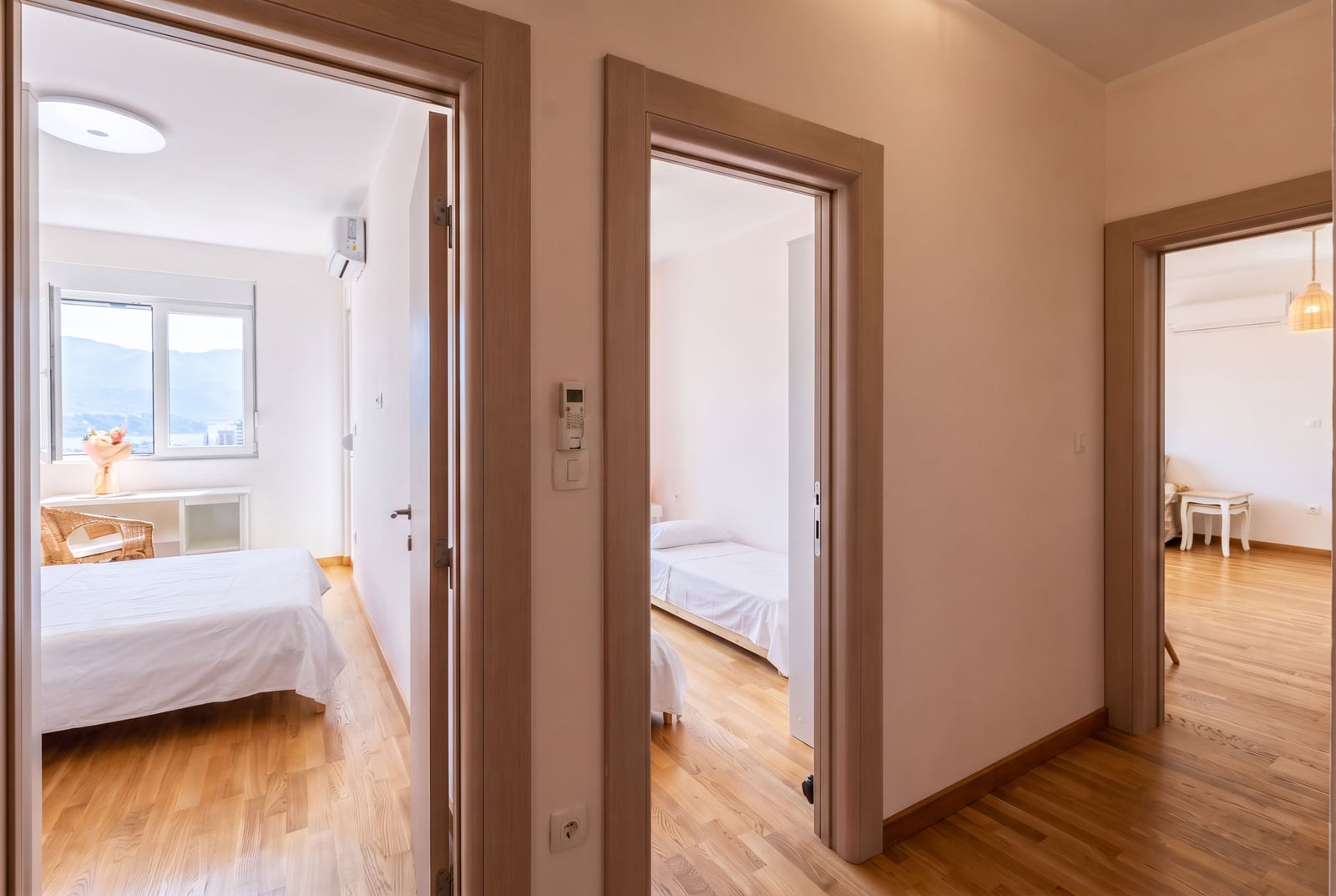 Bright hallway with interior doors and bedrooms in a Budva apartment, Montenegro, featuring mountain views and parquet flooring.