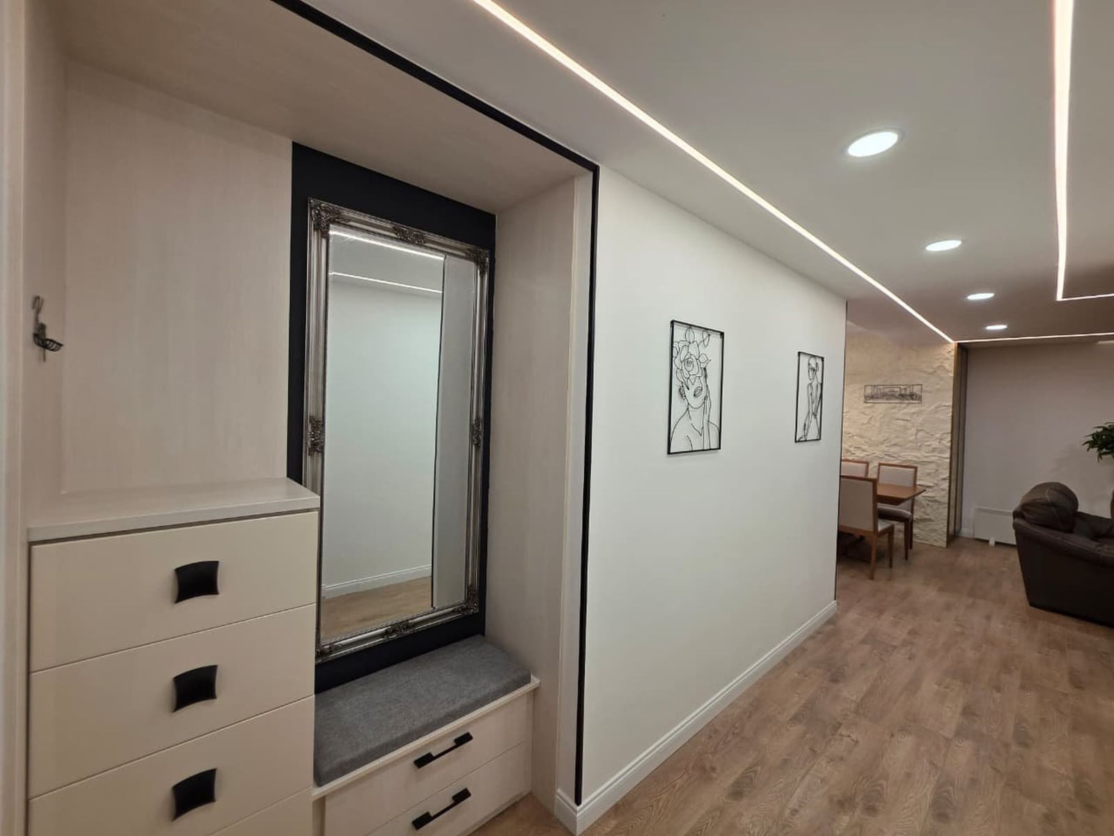 Modern living room in an apartment in Bečići, Montenegro: built-in mirrored wardrobe, lighting, and dining area.