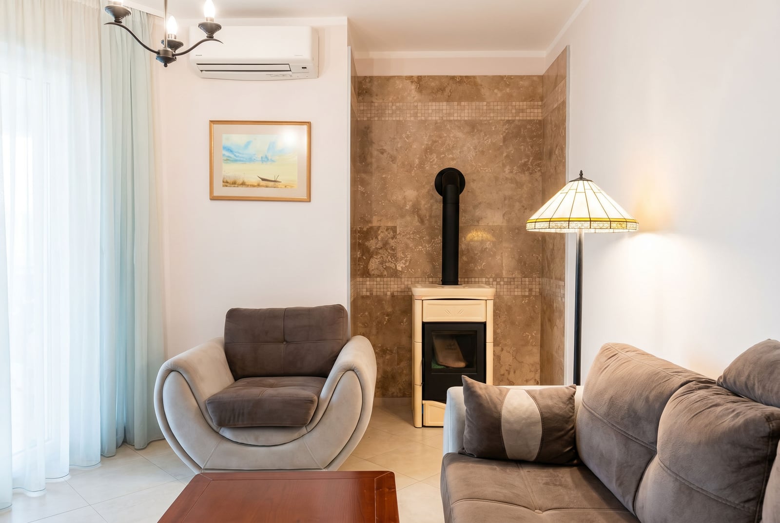 Living room in an apartment in Bar, Montenegro: modern furniture, stone-finished fireplace, air conditioning, and floor lamp.
