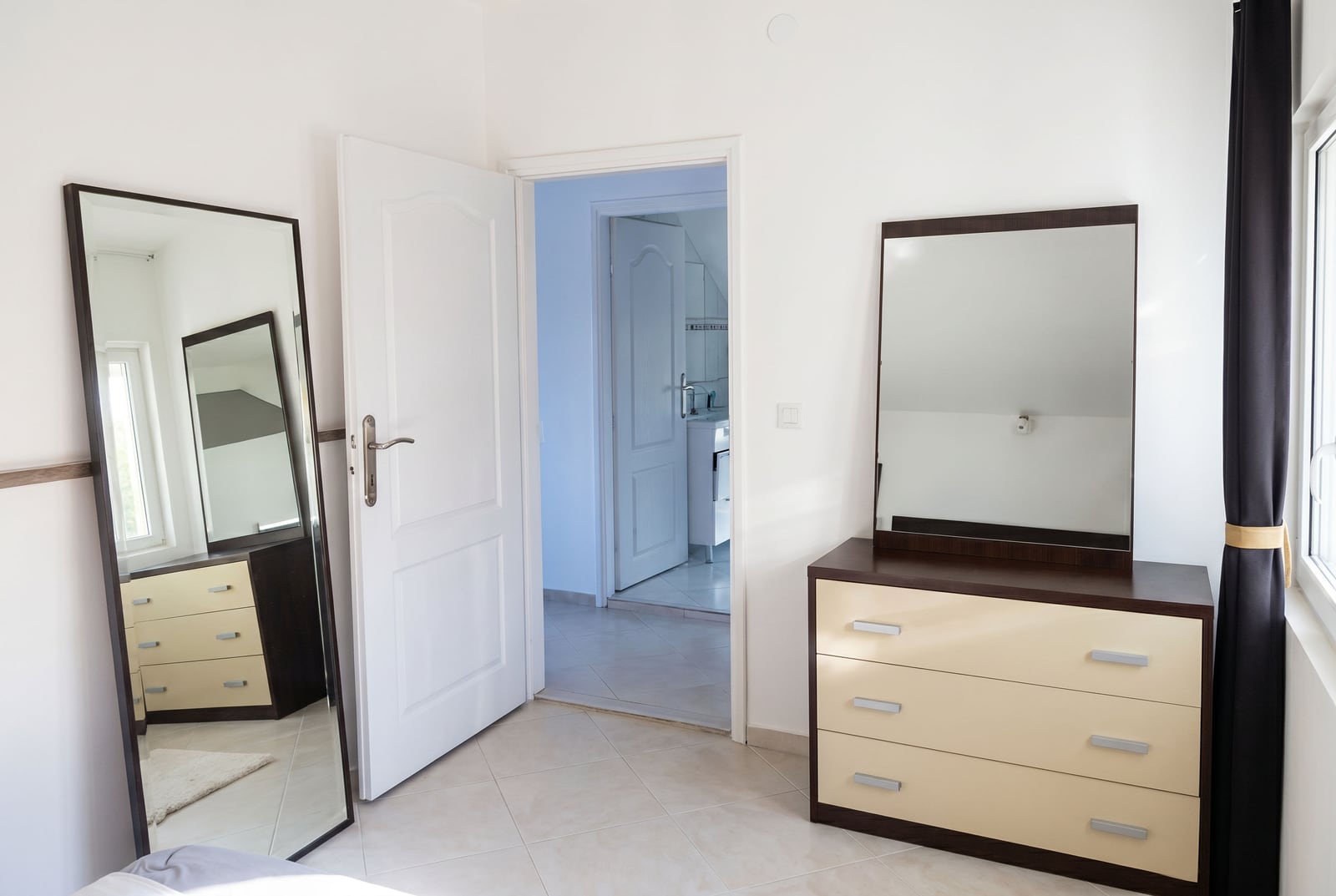 Bedroom in a house in Krašići, Montenegro: a bright room with a chest of drawers, a full-length mirror, and access to the bathroom.
