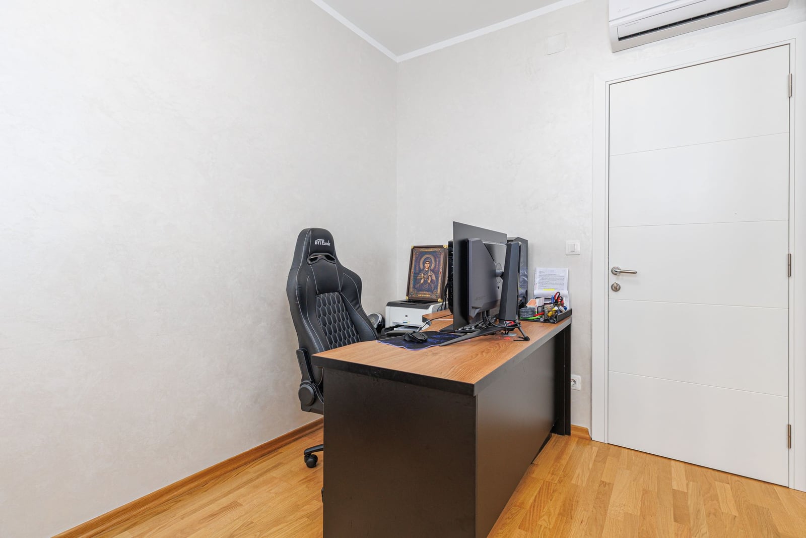 Home office in an apartment in Bečići, Montenegro: computer desk, gaming chair, light-colored interior, and air conditioning.