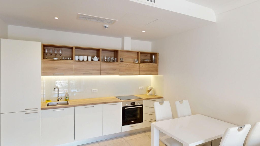 Modern kitchen with white facades and a dining area in the Lustica Bay apartments, Luštica, Montenegro.