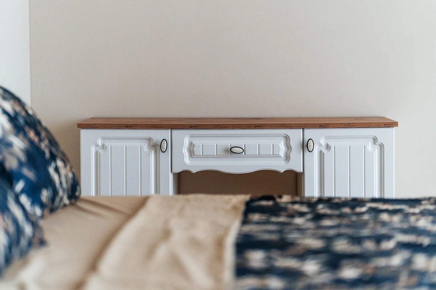 White vintage console with a wooden top in the bedroom of an apartment in Budva, Montenegro.