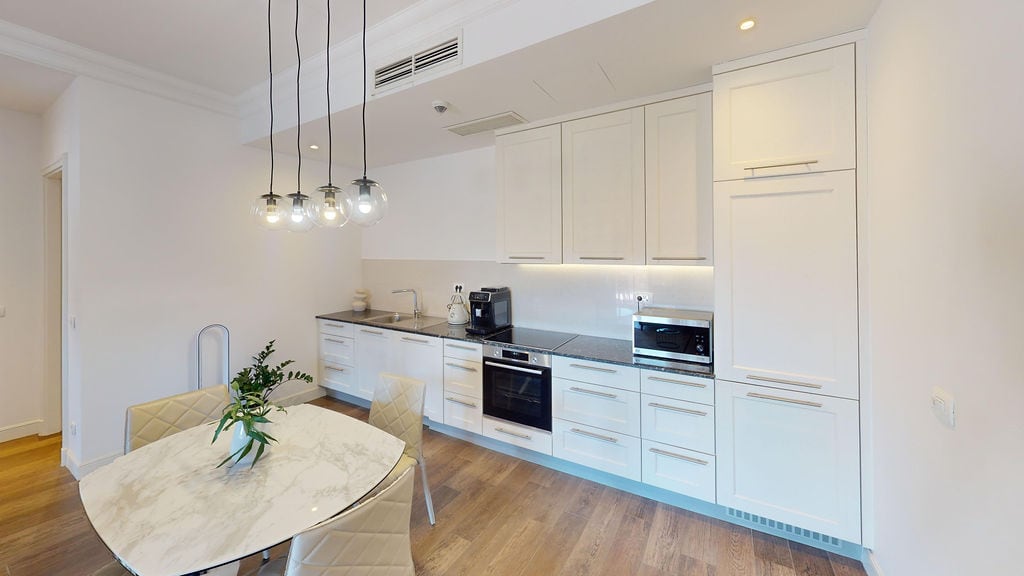 Modern kitchen with white cabinetry and a marble table in an apartment within a residential complex in Luštica, Montenegro.