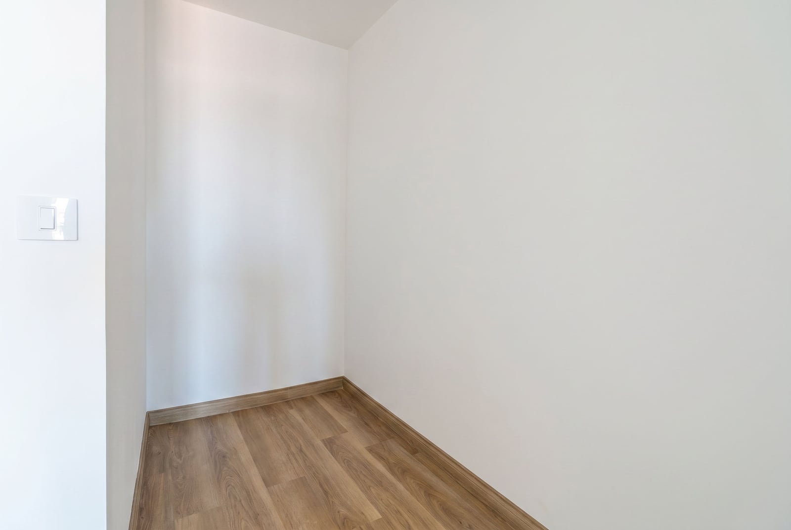 Bright empty niche in a Budva, Montenegro apartment: white walls and high-quality wood-look laminate flooring in the interior.