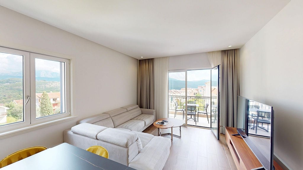 Bright living room with access to the terrace in an apartment in Lustica Bay, Montenegro: modern furniture and mountain views.