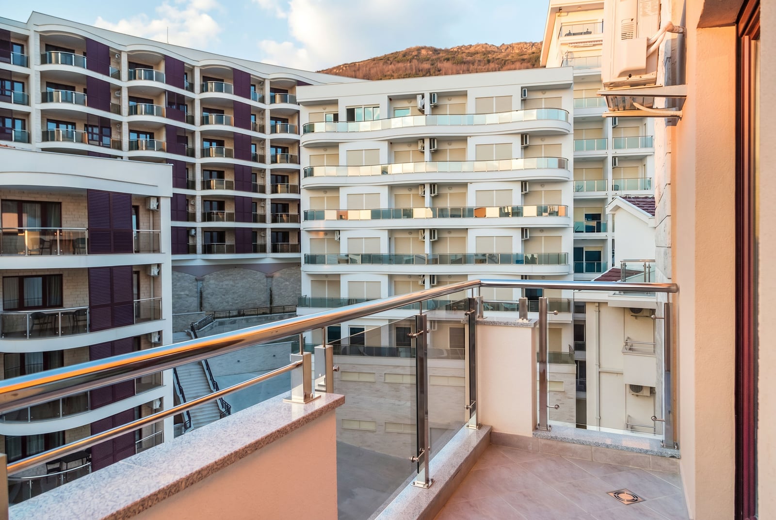 View from the balcony of a modern apartment in a residential complex in Bečići, Montenegro, featuring a panoramic view of neighboring buildings.