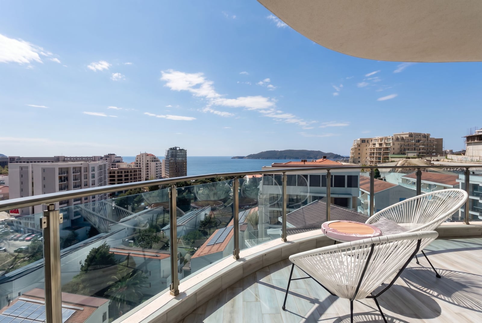 Balcony with wicker furniture and panoramic views of the sea and the city of Bečići, Montenegro in modern apartment No. 2631.