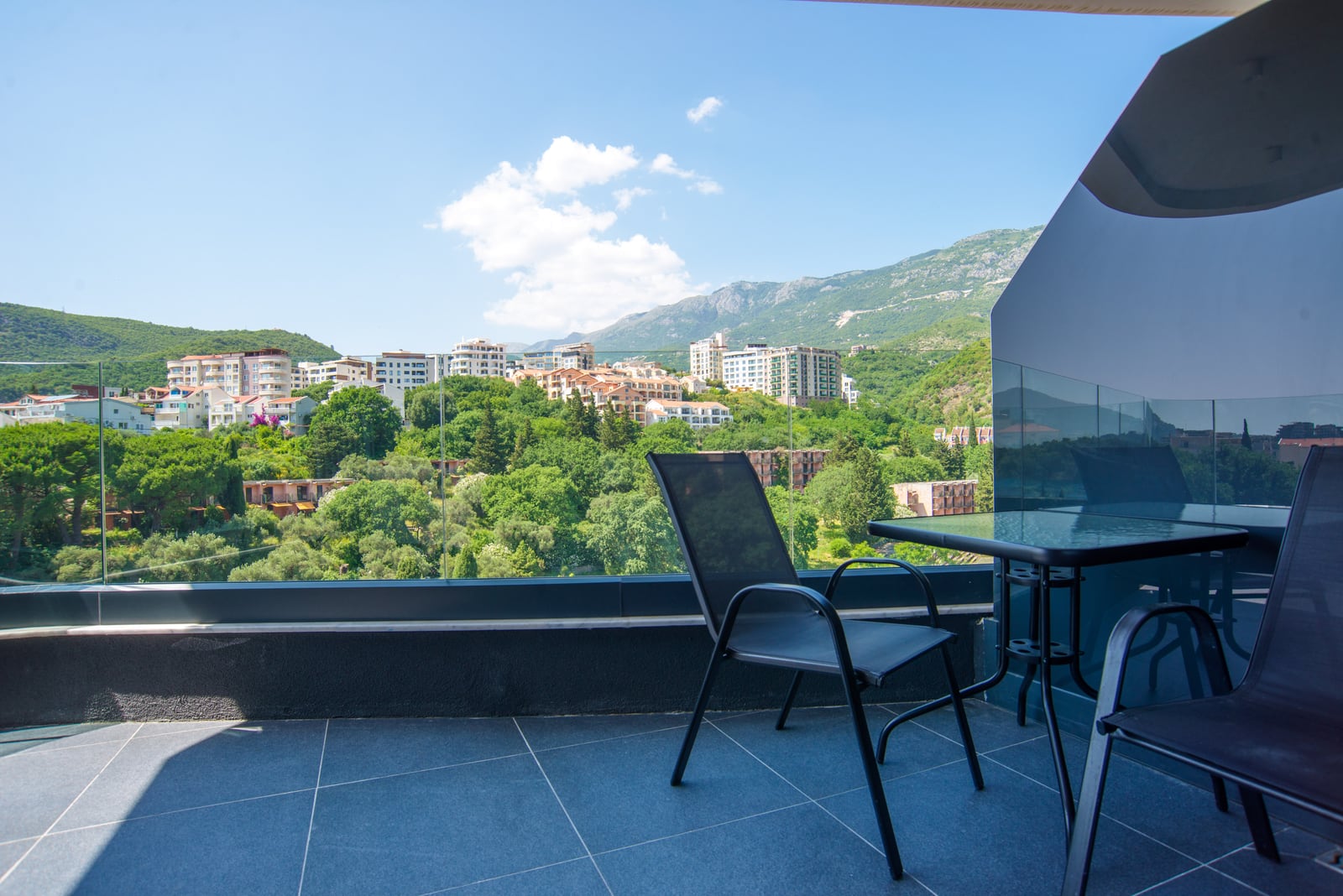 Terrace with furniture and panoramic view of the mountains and the town of Bečići, Montenegro. Apartment No. 2652 with a modern balcony.