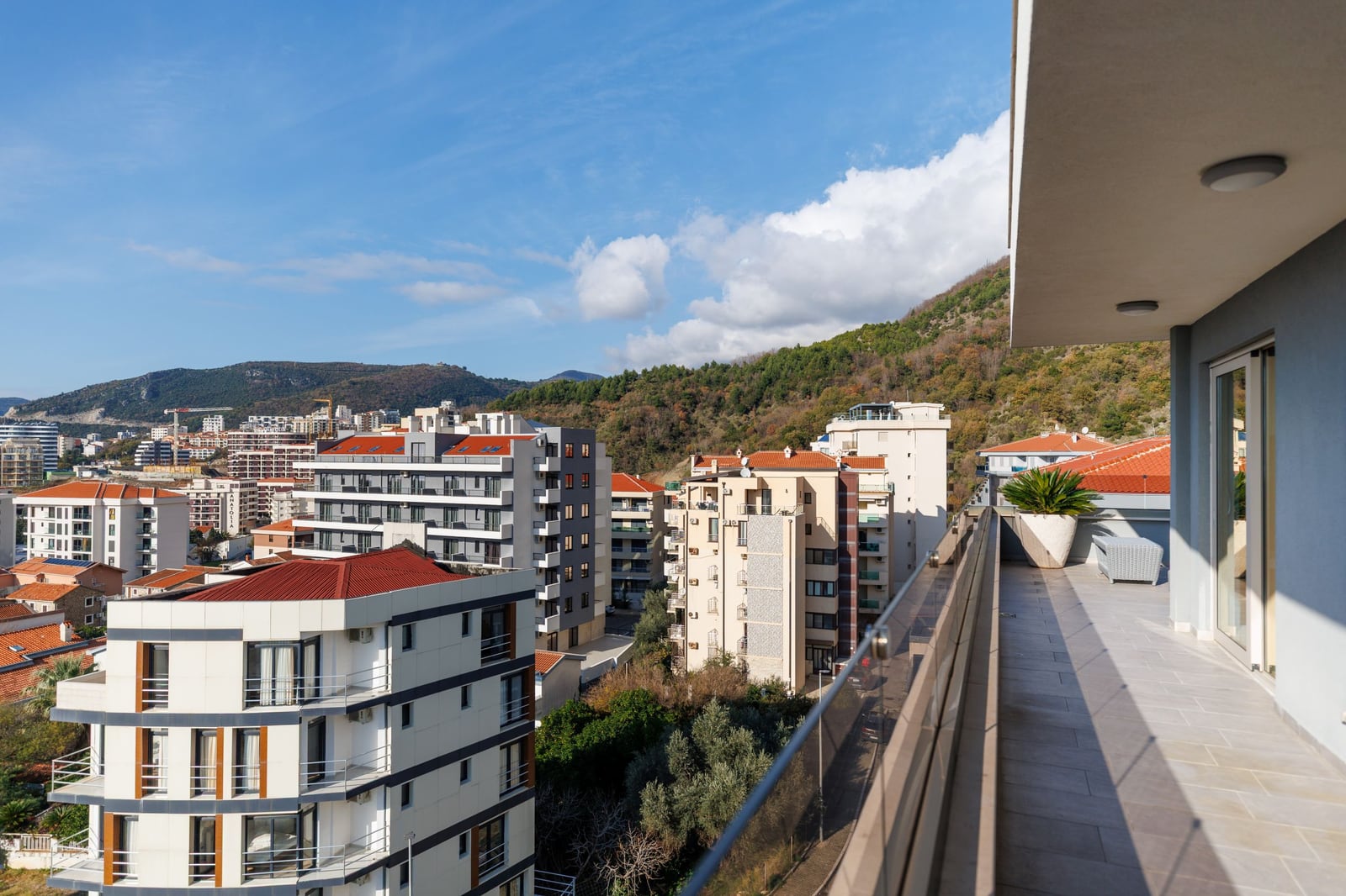View from the penthouse terrace in Bečići, Montenegro: modern balcony with a panoramic view of the mountains and the residential complex.