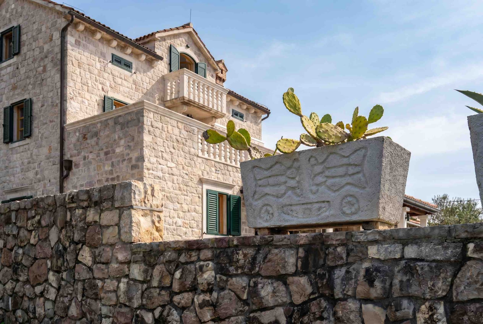 Stone house in Mediterranean style with a balcony and cacti in Luštica, Montenegro. Natural stone facade.