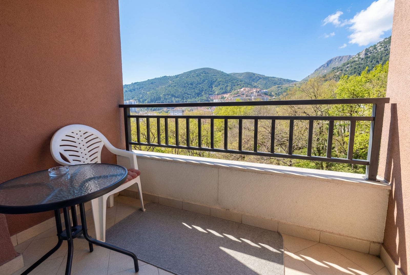 Balcony with furniture and panoramic mountain views in an apartment in Budva, Montenegro. Sunny terrace overlooking nature.