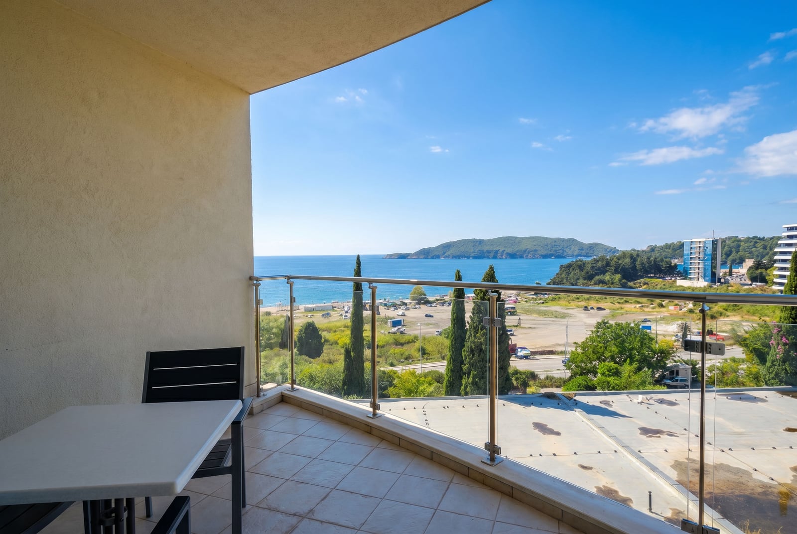 Balcony with furniture and panoramic sea and beach view in a residential complex in Bečići, Montenegro.