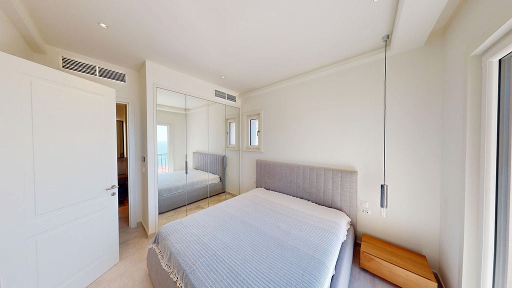 Modern bedroom with a double bed and mirrored wardrobe in a villa in Luštica, Montenegro.