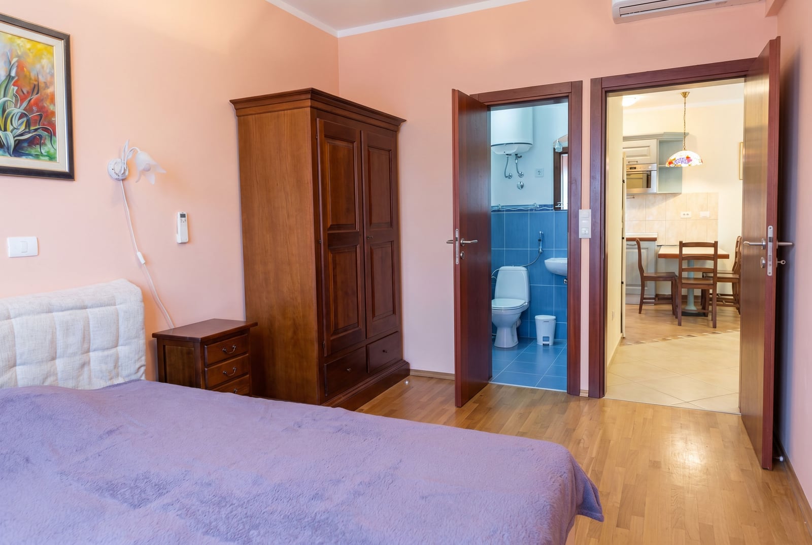 Bedroom in an apartment in Bar, Montenegro: wooden wardrobe, double bed, view of the bathroom and kitchen.