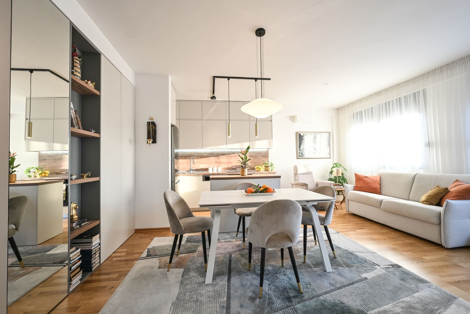 Modern living room with kitchen in an apartment in Tivat, Montenegro: dining area, light-colored furniture, and parquet flooring.