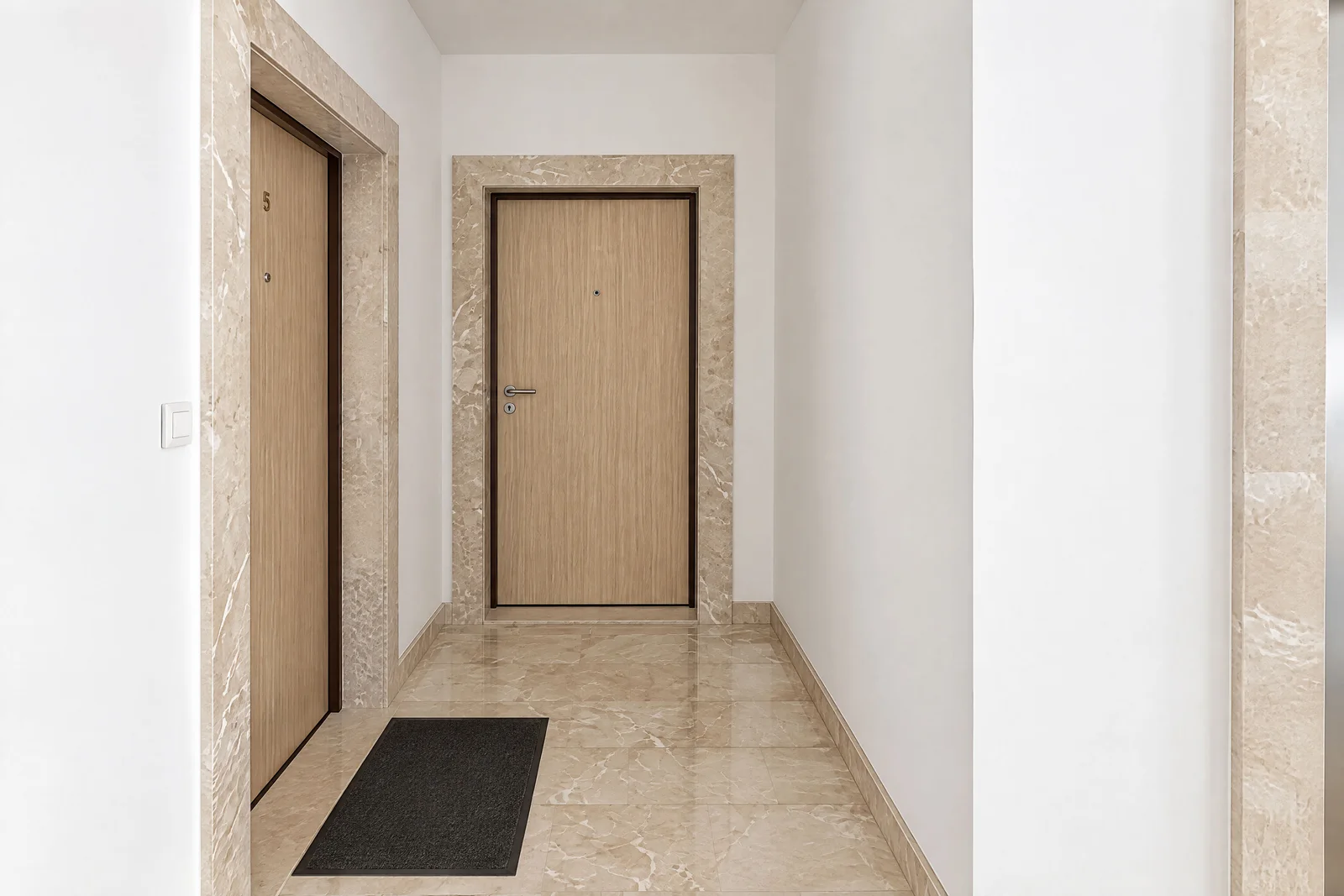 Bright hallway with marble flooring and wooden apartment doors featuring a dark mat.