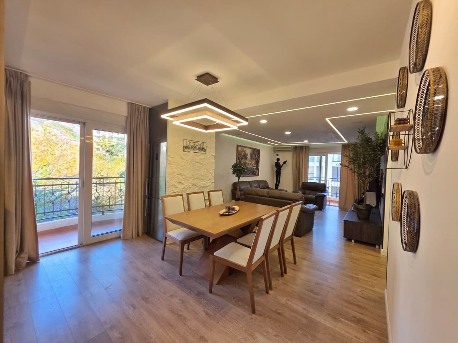 Modern living room with dining area in an apartment, Becici, Montenegro: stylish furniture, decor, and access to the balcony.