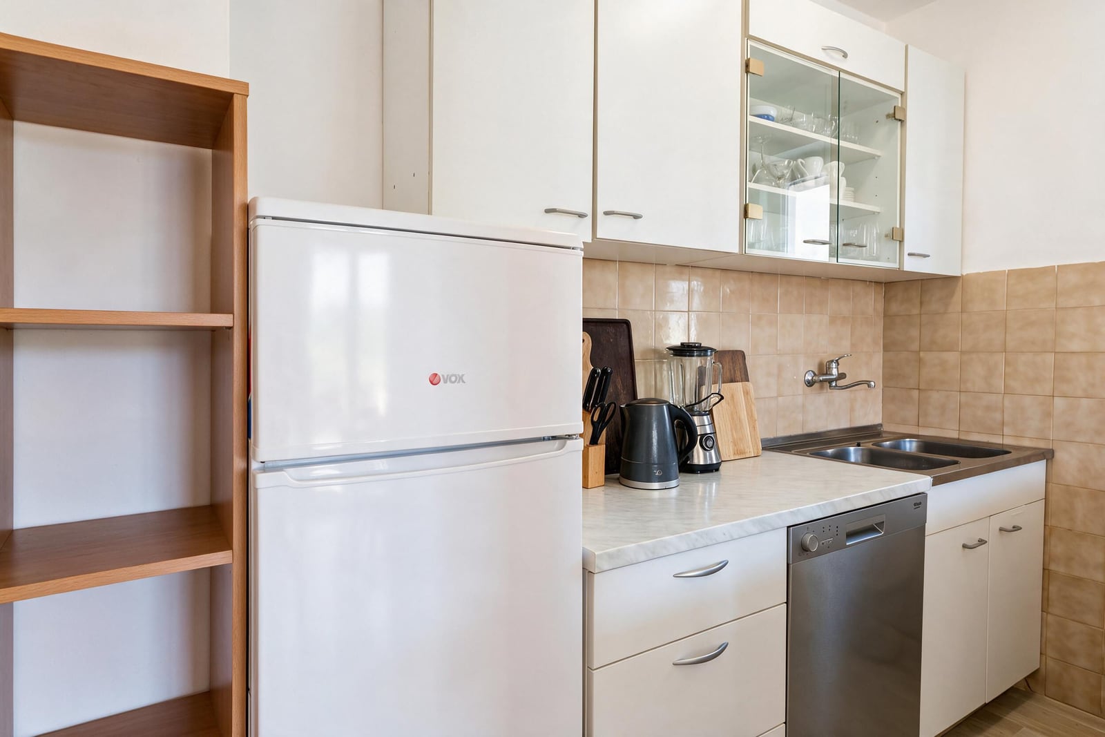 Kitchen featuring a white fridge, built-in dishwasher, sink, and upper cabinets with glass doors.