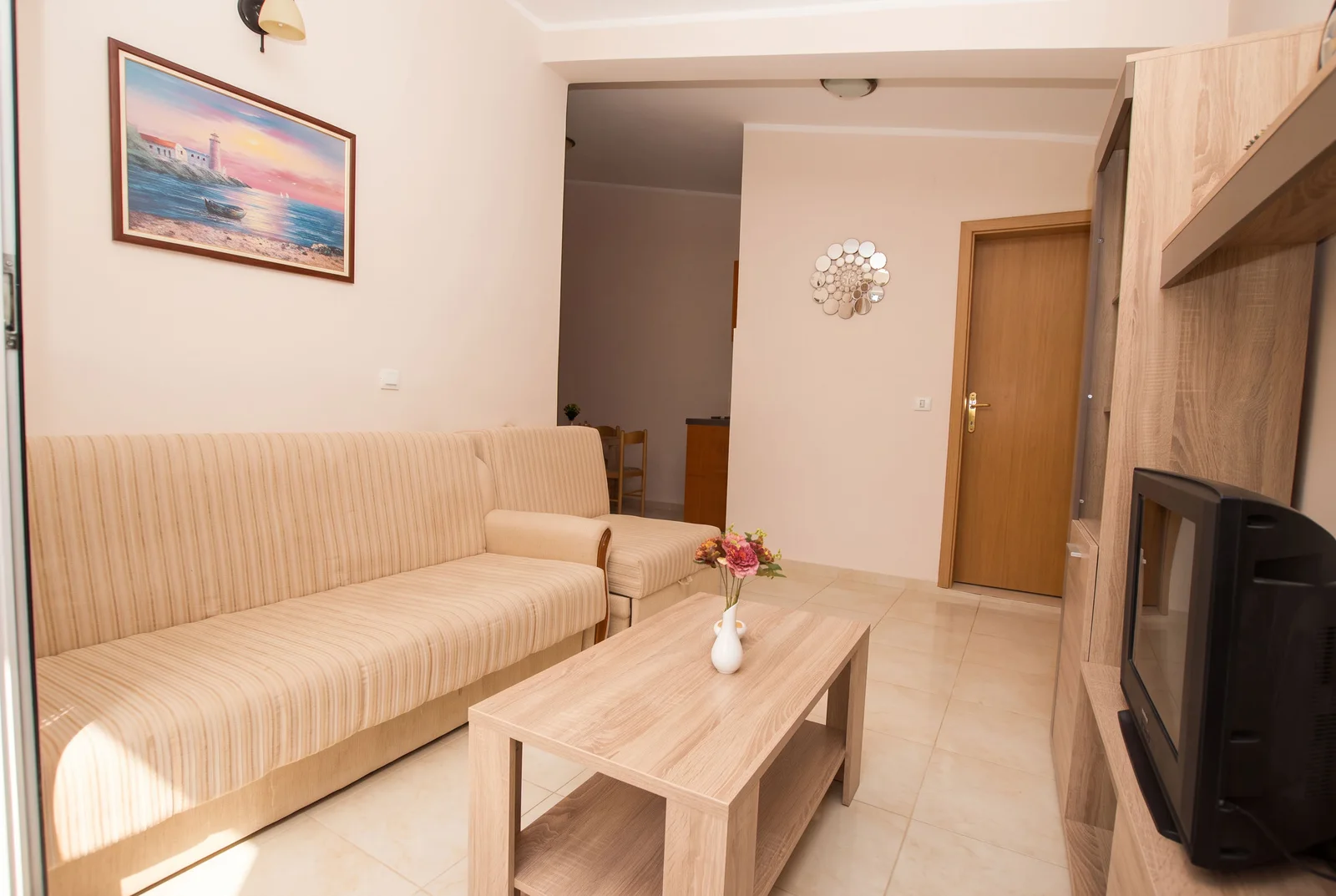 Living room featuring a beige sofa, wooden coffee table, and TV unit.