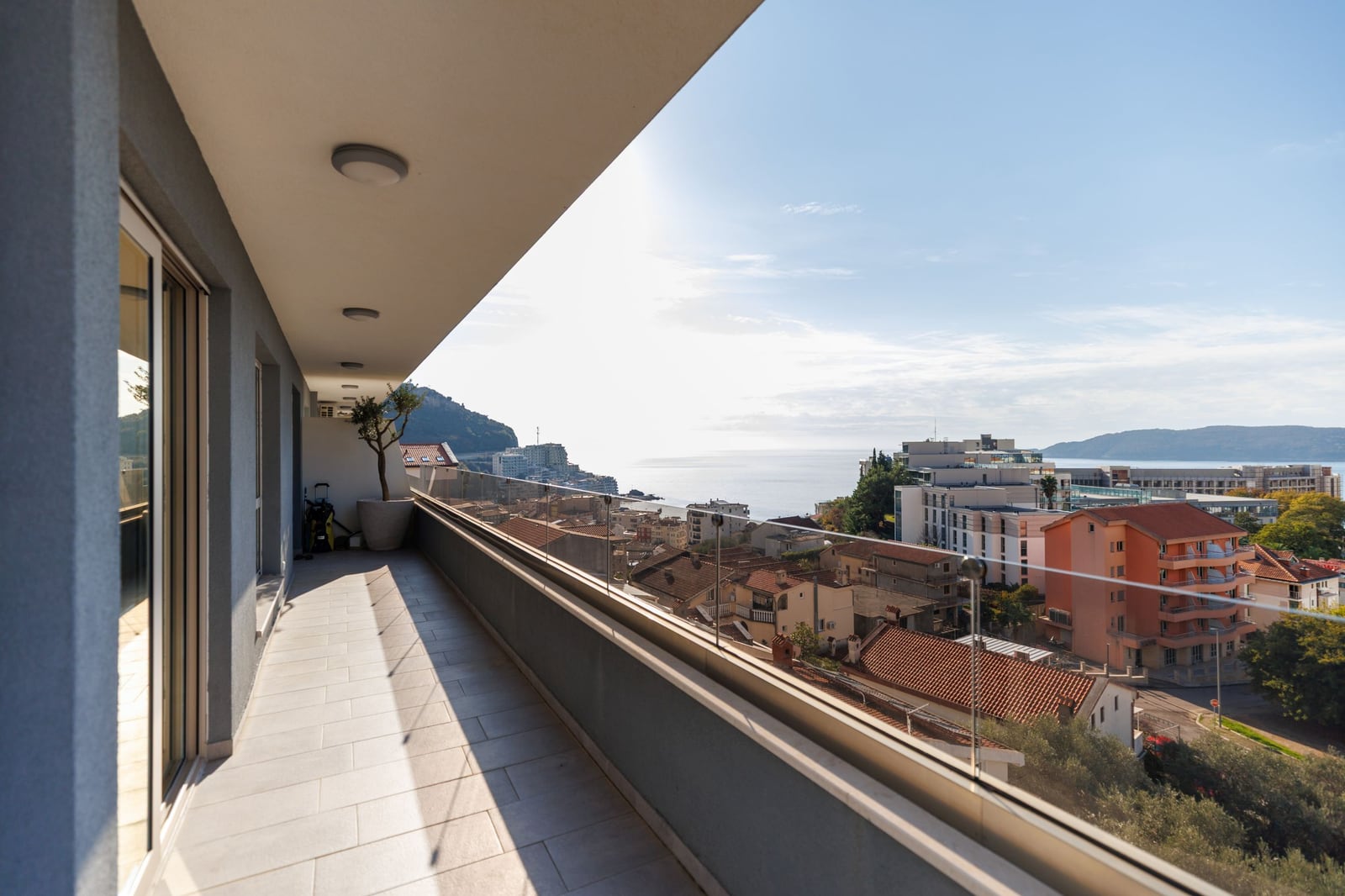 Spacious penthouse balcony in Becici, Montenegro, with panoramic views of the sea, mountains, and the cityscape.