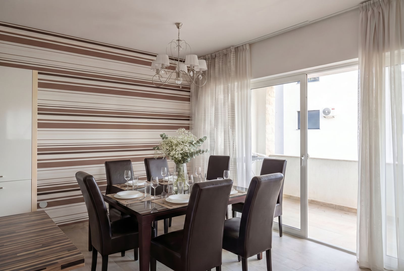 Modern living room with a dining area in an apartment, Kumbor, Montenegro: dark chairs, table, and balcony access.