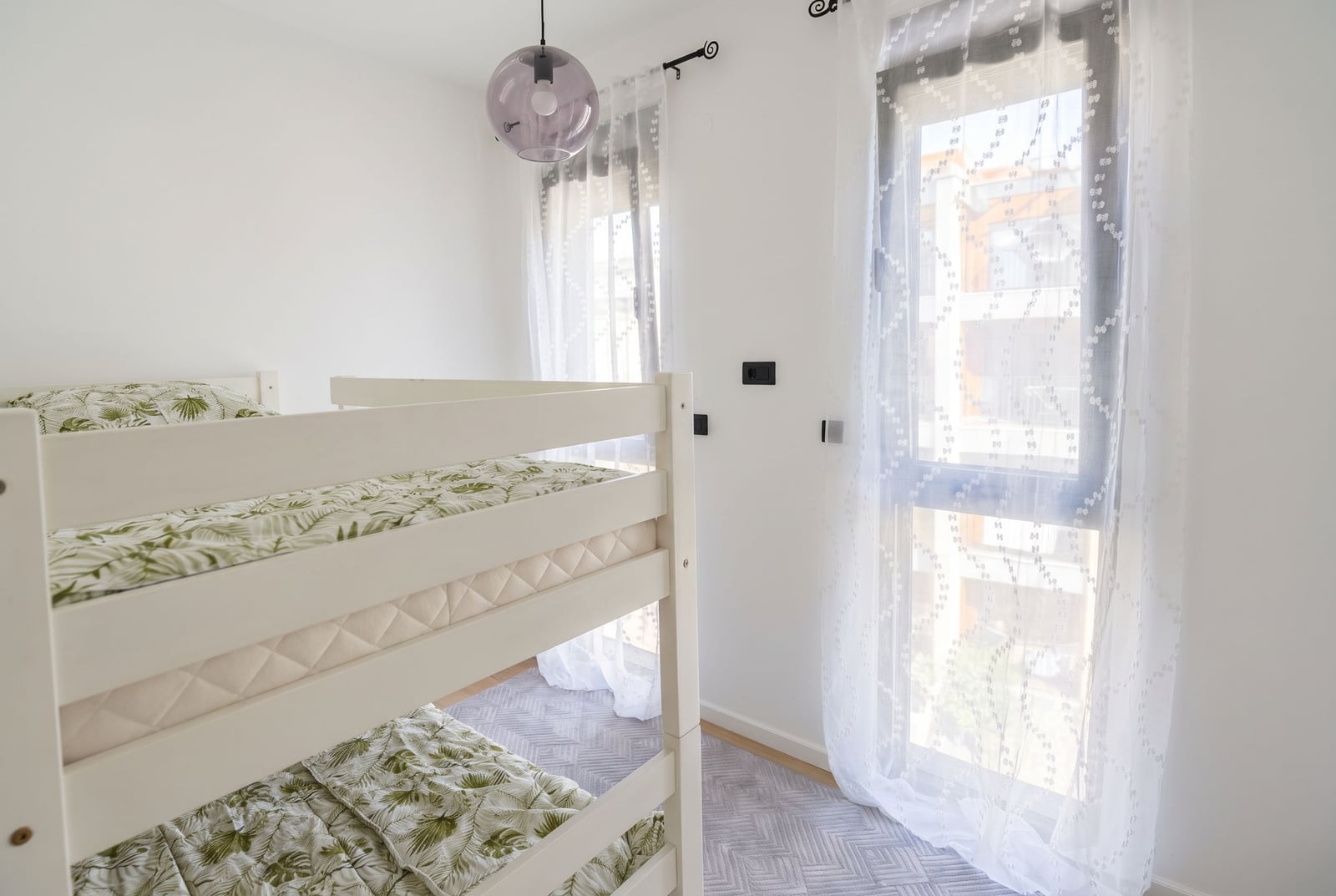 Children's bedroom with a white bunk bed and panoramic window in an apartment in Tivat, Montenegro.