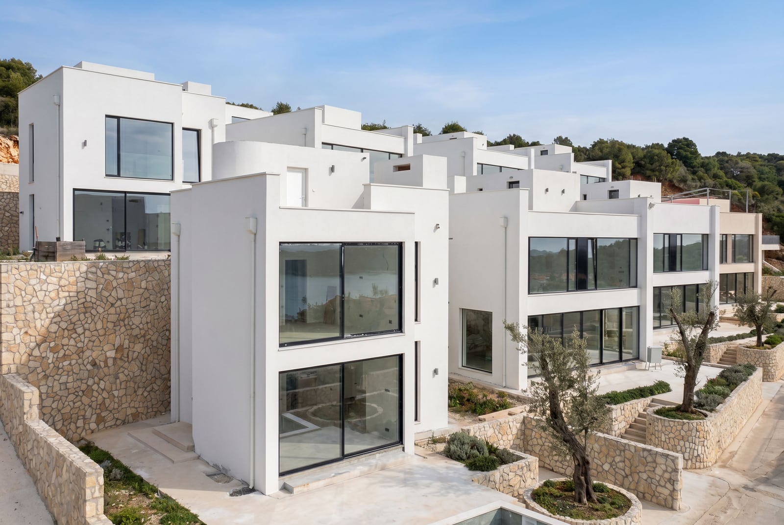 Modern white villas with panoramic windows and stone detailing in Kumbor, Montenegro, exterior view.