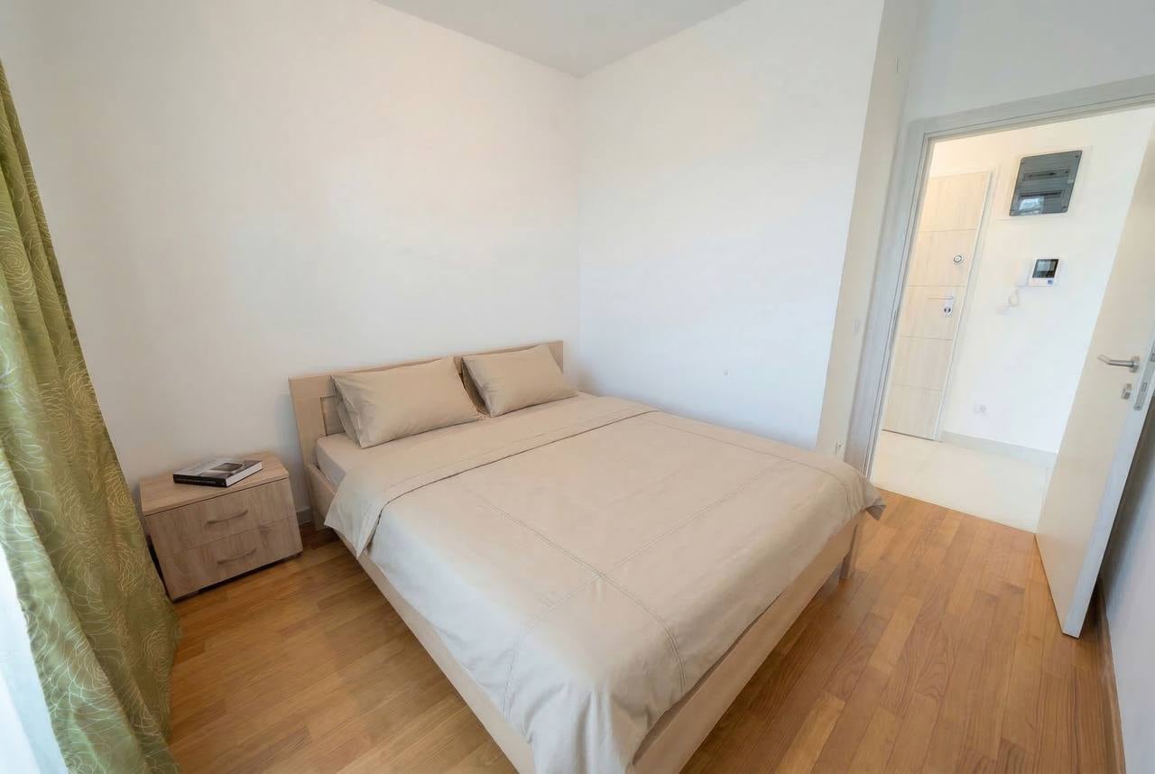 Bright bedroom with a double bed and parquet flooring in an apartment for sale, Becici, Montenegro.